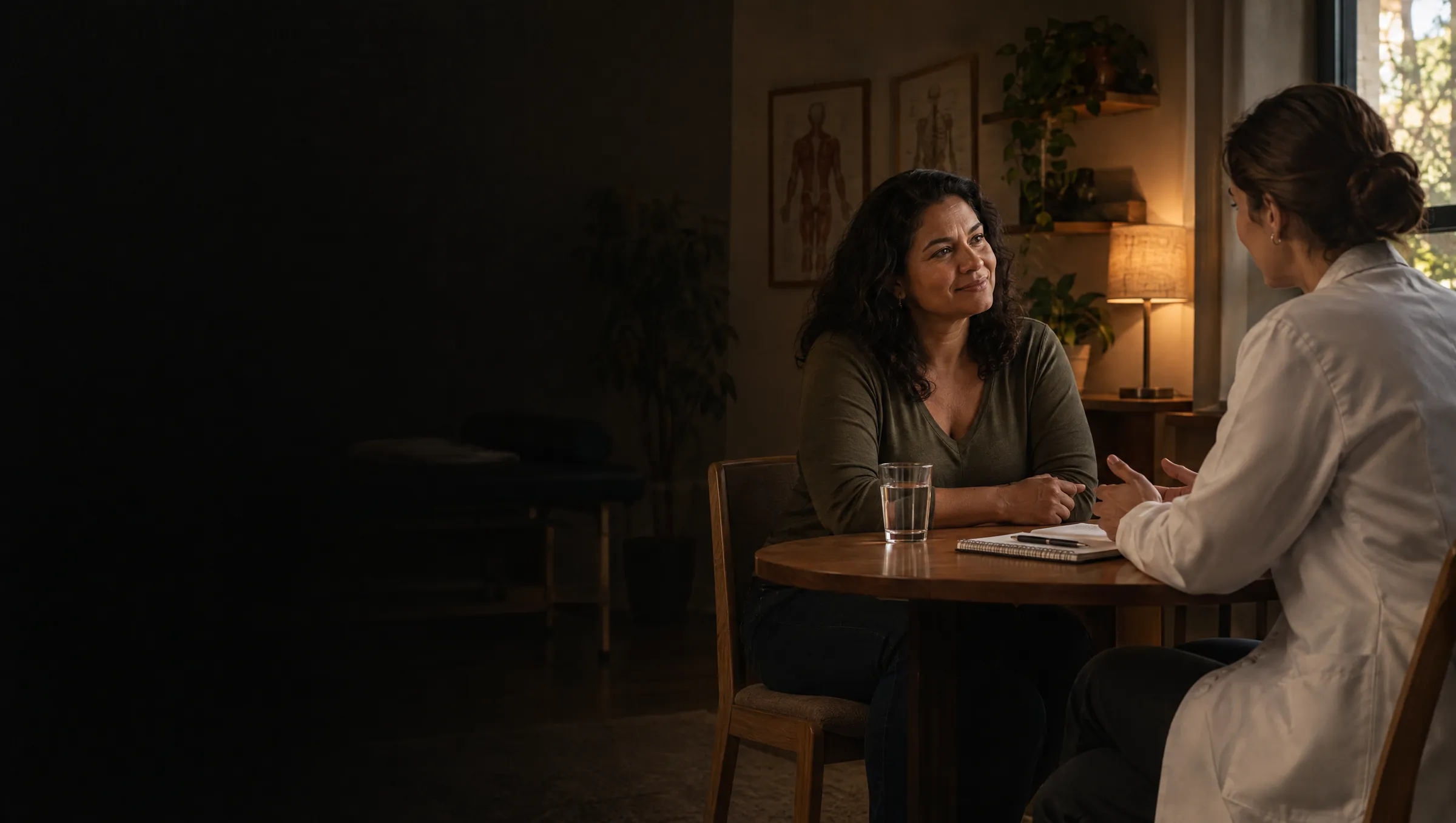 Paciente e fisioterapeuta conversam sentadas à mesa na primeira consulta